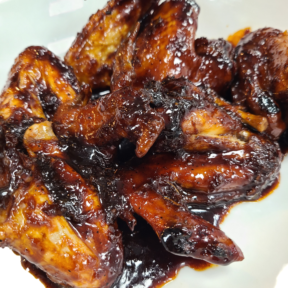 Glazed chicken wings on a white plate.