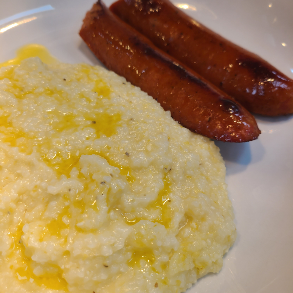 Grilled sausage served with buttery grits.